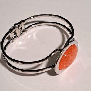 Silver tone metal clamp bracelet with large orange oval design